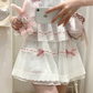 Close-up of the white and pink Sweet Love Lace Bow Skort, highlighting the heart lace trim, layered mesh, and pink bow accents.