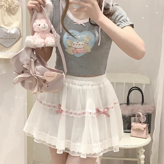 Model wearing the white and pink Sweet Love Lace Bow Skort with a gray top for a sweet coquette look.