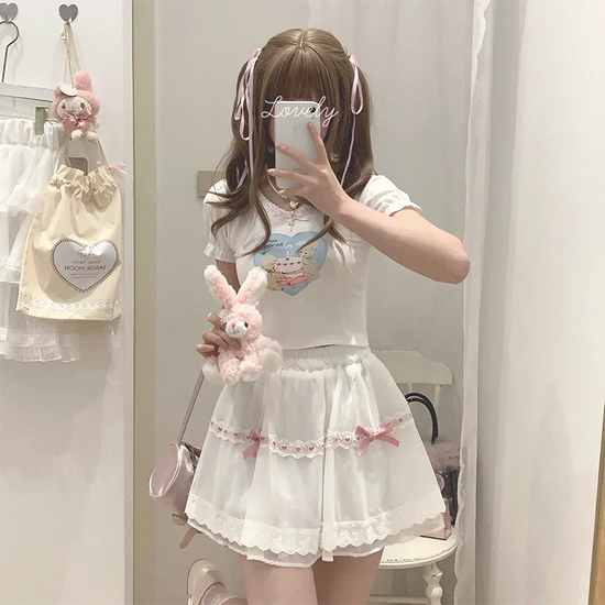 Model wearing the white and pink Sweet Love Lace Bow Skort styled with a graphic tee and plush bunny bag.
