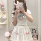 Mirror selfie of the white and pink Sweet Love Lace Bow Skort, showcasing the layered mesh and mini silhouette.
