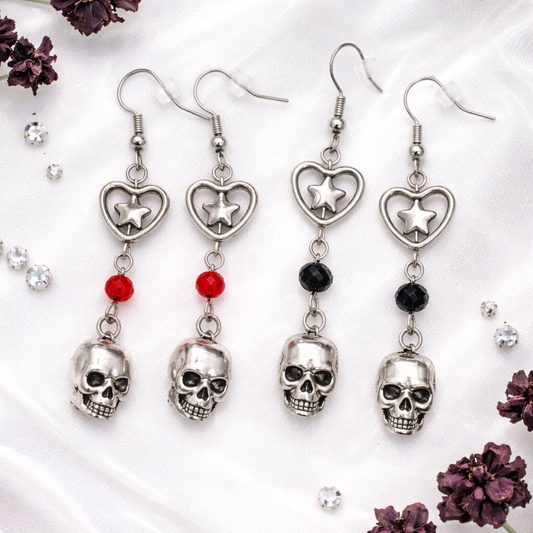 Til Death Do We Sparkle Earrings featuring silver skull charms with heart star details in red and black crystal bead variants.