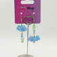 Two Moody Originals Candy Bite Bat Earrings featuring pastel blue bat charms with green, blue, and yellow glass and acrylic beads in mismatched opposite designs hanging on a Two Moody jewelry display.