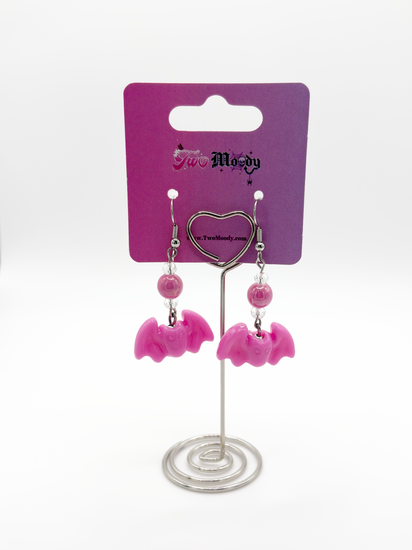 Two Moody Originals Candy Bite Bat Earrings hot pink version displayed on stand