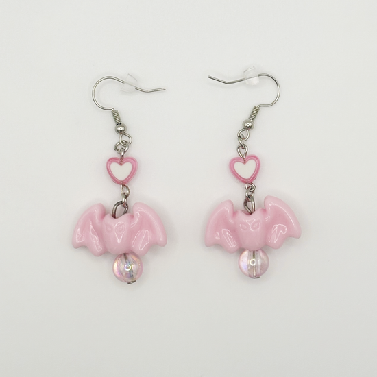 Two Moody Originals Candy Bite Bat Earrings in soft pink with heart connector and iridescent bead