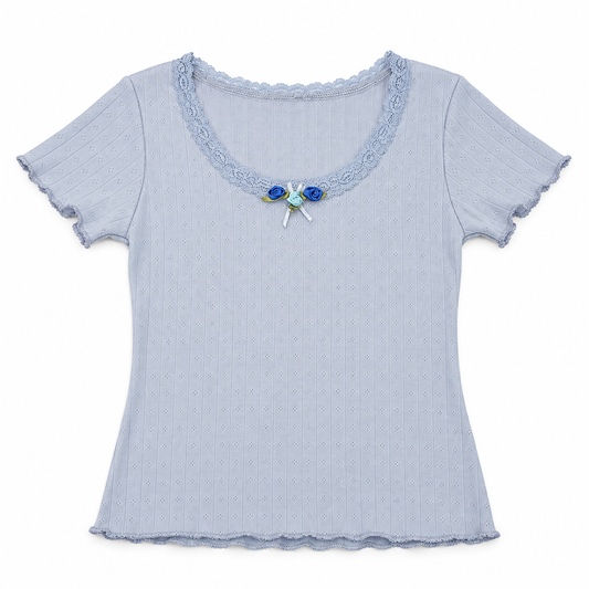 Front flat lay of the blue Two Moody Originals: Floral Daydream Top with pointelle texture, scalloped lace, and three blue rose appliqués with a bow.