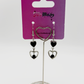 Two Moody Originals: Lovesick Charm Earrings with black crystal heart accents and glossy black enamel heart charms on a Two Moody jewelry display.