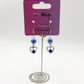 Two Moody Originals: Lovestruck Charm Earrings with iridescent blue beads and blue and clear crystal heart details on a Two Moody jewelry display.