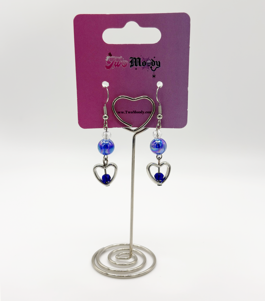 Two Moody Originals: Lovestruck Charm Earrings with iridescent blue beads and blue and clear crystal heart details on a Two Moody jewelry display.