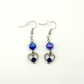 Two Moody Originals: Lovestruck Charm Earrings with iridescent blue beads, clear crystal accents, silver heart charms, and deep blue crystal centers.