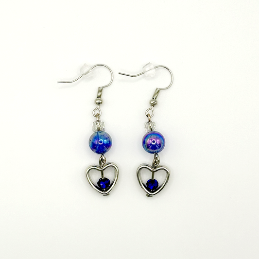Two Moody Originals: Lovestruck Charm Earrings with iridescent blue beads, clear crystal accents, silver heart charms, and deep blue crystal centers.