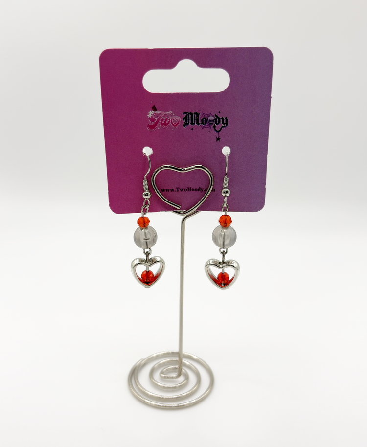 Two Moody Originals: Lovestruck Charm Earrings displayed with smoky black beads and red and red orange crystal accents on a Two Moody jewelry display.
