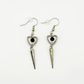 Two Moody Originals: Pierced Heart Dagger Earrings with silver open heart charms, black crystal accents, and dangling silver dagger details.