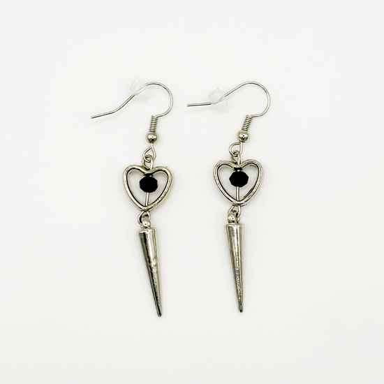 Two Moody Originals: Pierced Heart Dagger Earrings with silver open heart charms, black crystal accents, and dangling silver dagger details.