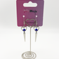 Two Moody Originals: Pierced Heart Dagger Earrings displayed on branded packaging with silver open heart charms, blue crystal accents, and dangling dagger details.