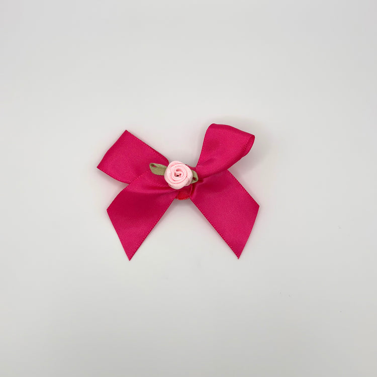 Front of the small decorated Two Moody Originals: Signature Bow Clips in the color hot pink with a light pink rose in the center