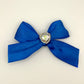 Front of the small decorated Two Moody Originals: Signature Bow Clips in the color royal blue with a heart rhinestone center