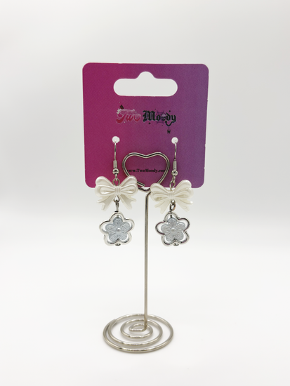 Two Moody Originals: Soft Bloom Bow Earrings displayed on branded packaging with white bow details and floral charms.