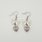 Two Moody Originals: Softhearted Bow Earrings with white bow charms, silver heart pendants, and pink faux pearl accents on silver hooks.