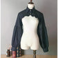 Front view of the black Ultra Cropped Layering Blouse with the collar buttoned, featuring golden rose buttons, gathered trim, and dramatic long sleeves.