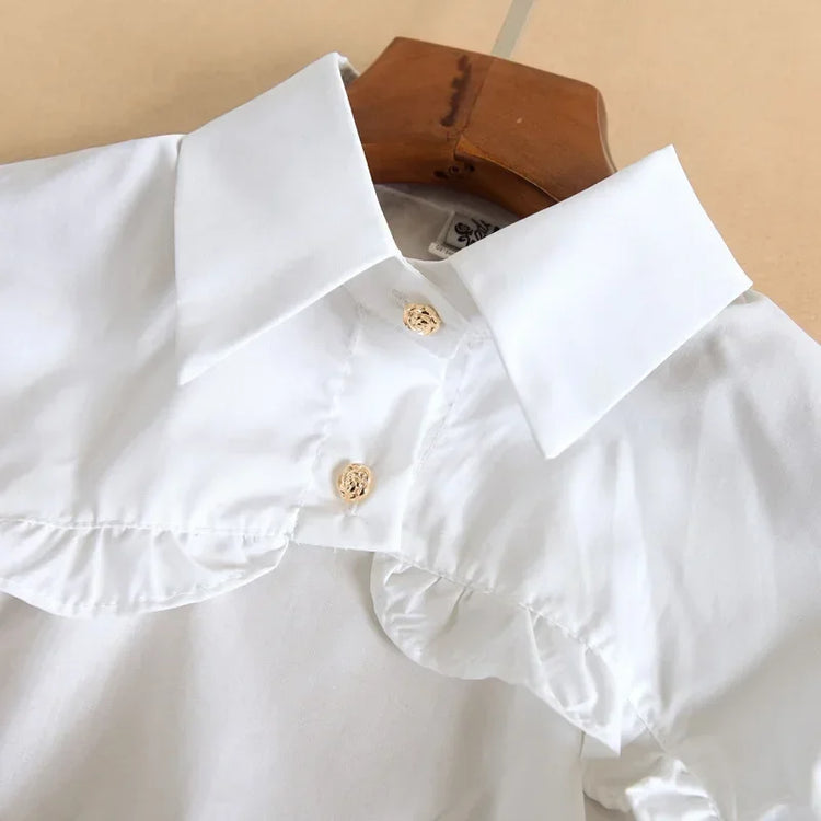 Close-up of the white Ultra Cropped Layering Blouse collar featuring golden rose buttons and gathered detailing.