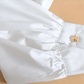 Close-up of the white Ultra Cropped Layering Blouse cuff with a golden rose button and gathered sleeve.