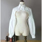 Front view of the white Ultra Cropped Layering Blouse with the collar buttoned, featuring golden rose buttons, gathered trim, and dramatic long sleeves.