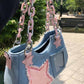 Side-angle view of the Y2K Harajuku Star Denim Chain Bag in light blue with a pink chain handle, shoulder strap, star appliqué, and clear pocket.