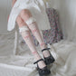 Model seated while wearing the white Kawaii Lace Bow Fishnet Stockings featuring fishnet stockings with dotted heart motifs, lace ruffle cuffs, and pink dotted lace bow accents.