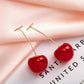 Sweet Cherry Earrings in red styled next to decorative props